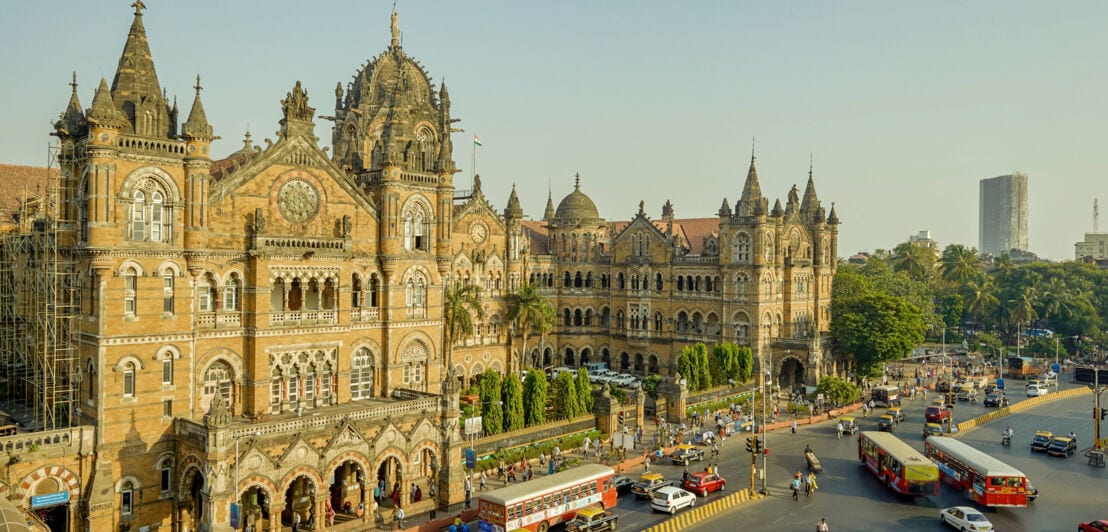 Historisches Gebäude mit gotischen Elementen in Mumbai mit Verkehr und Bussen.
