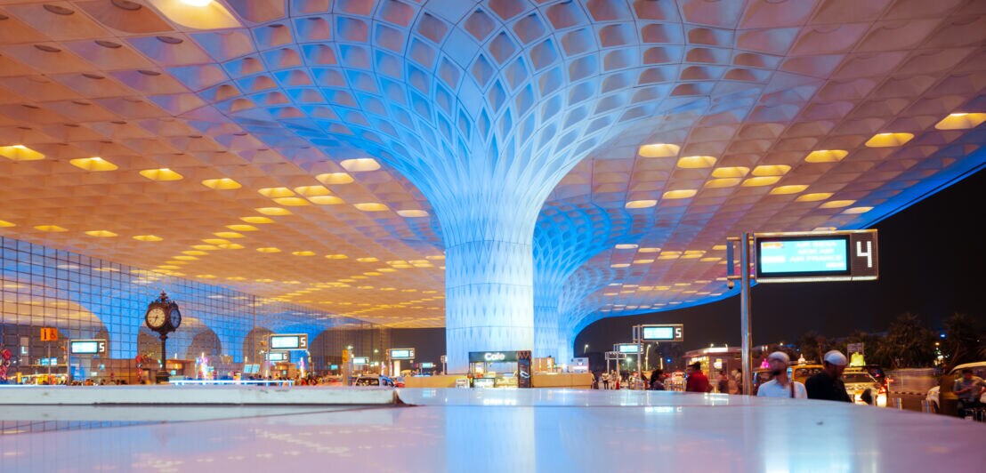 Großes, modernes Flughafen-Terminal in Mumbai mit markanter, baumförmiger Säule und blau-gelber Beleuchtung.