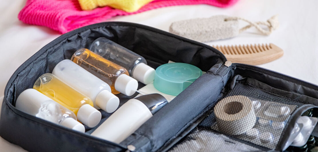 Nahaufnahme einer Kosmetiktasche mit gefüllten Plastikflaschen im Reiseformat.