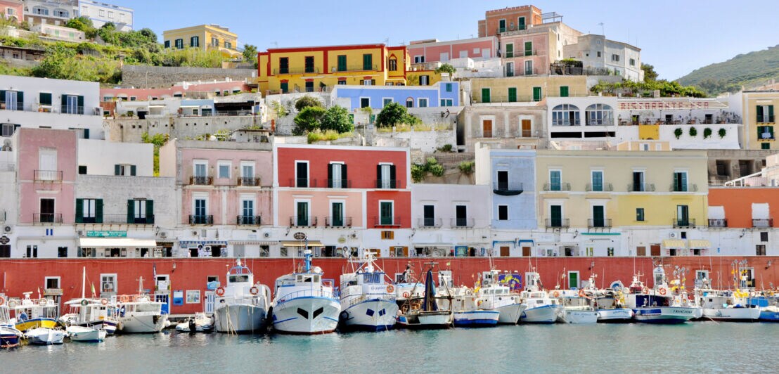 Bunte Häuser an einem Hang über dem Hafen von Ponza mit mehreren Booten im Wasser