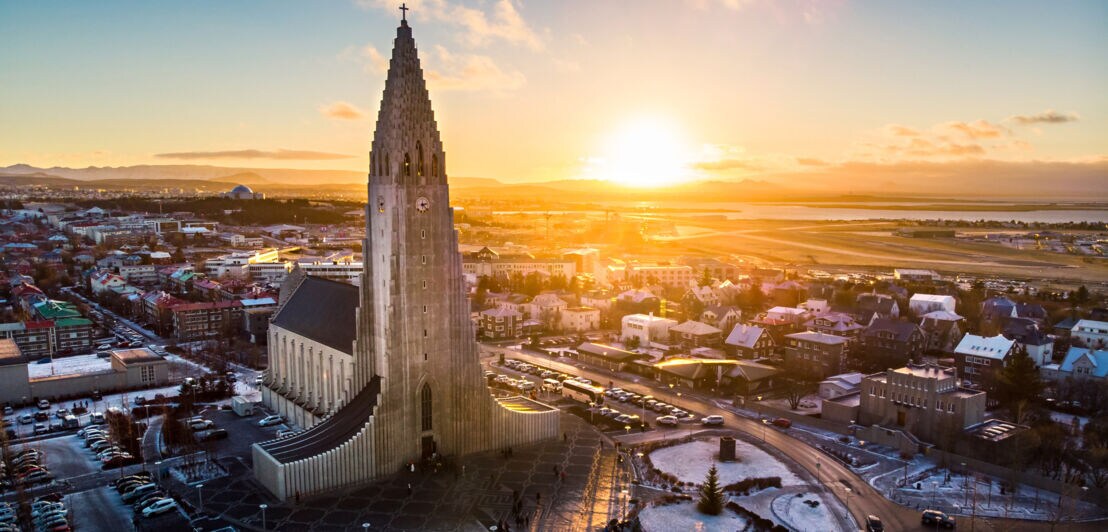 Hallgrímskirkja Kirche in Reykjavík bei Sonnenuntergang mit umliegender Stadt und leicht verschneitem Boden