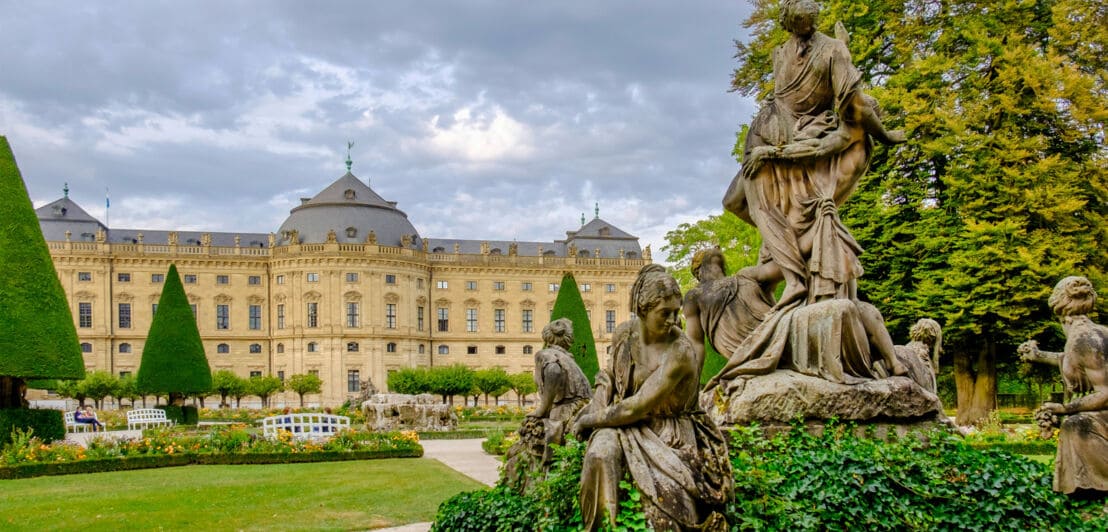 Barockes Residenzschloss mit Garten und Statuen im Vordergrund