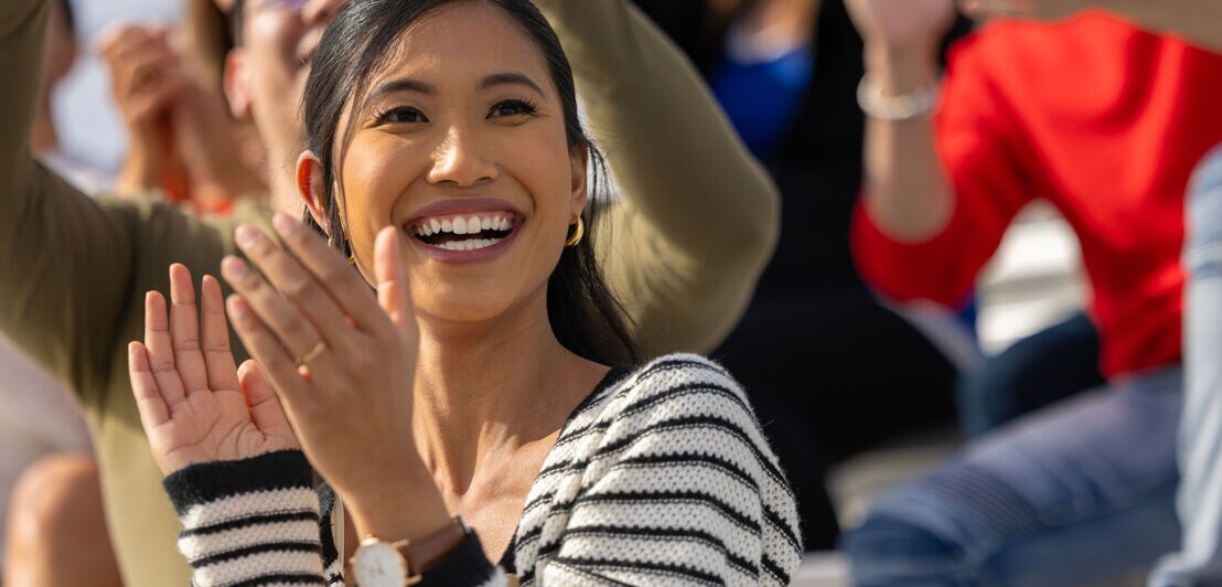 Junge Frau jubelt bei einer Sportveranstaltung.