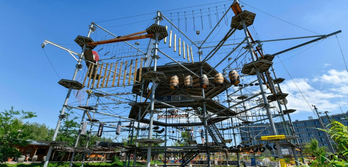 Hochseilgarten mit verschiedenen Kletterelementen und Plattformen unter blauem Himmel.