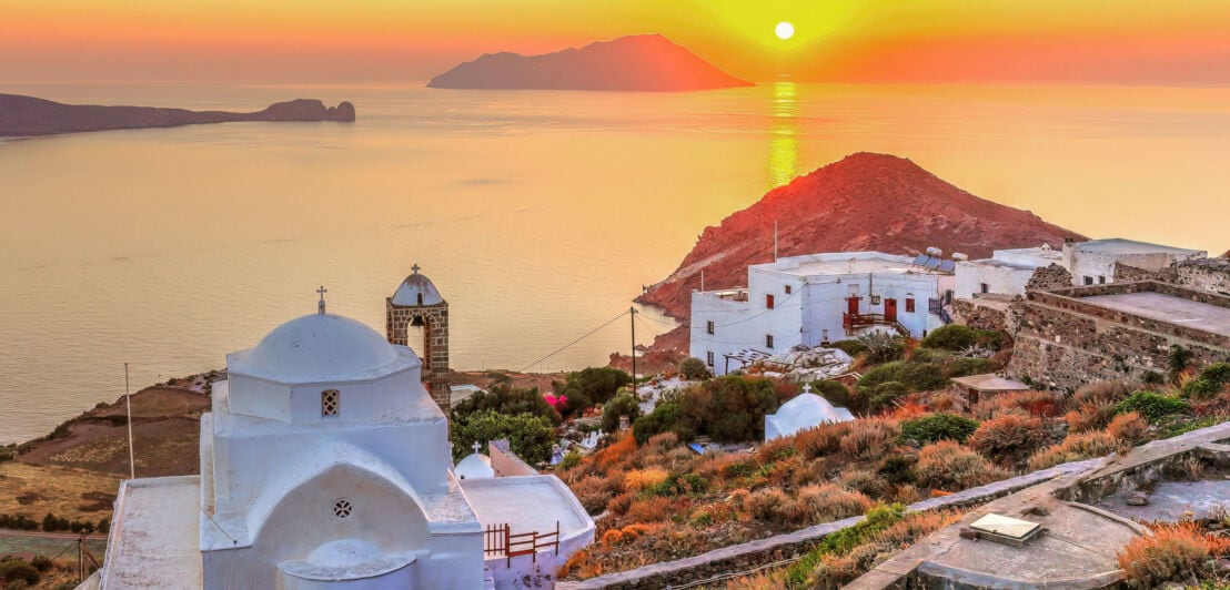 Blick aufs Meer bei Sonnenuntergang von einer Festung mit einer kleinen Kirche auf einem Hügel mit weiß getünchten Häusern.