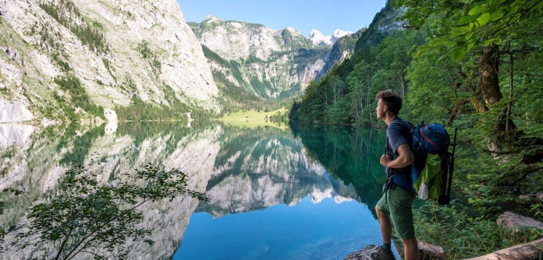Ein Mann mit Rucksack und in Wanderoutfit blickt auf den Königssee.