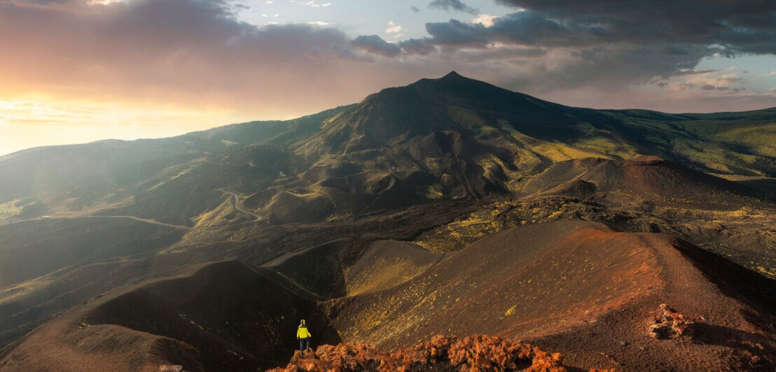 Blick von oben auf eine Person, die am Kraterrand steht.