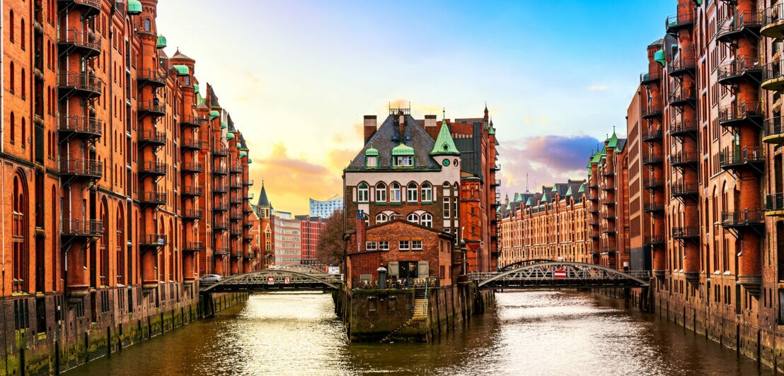 Historische Backsteingebäude entlang eines Kanals in der Speicherstadt Hamburg bei Sonnenuntergang.