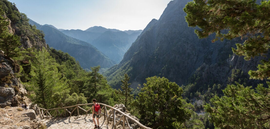 Eine Person beim Wandern in der Samaria-Schlucht auf Kreta, im Hintergrund Vegetation und Berggipfel.