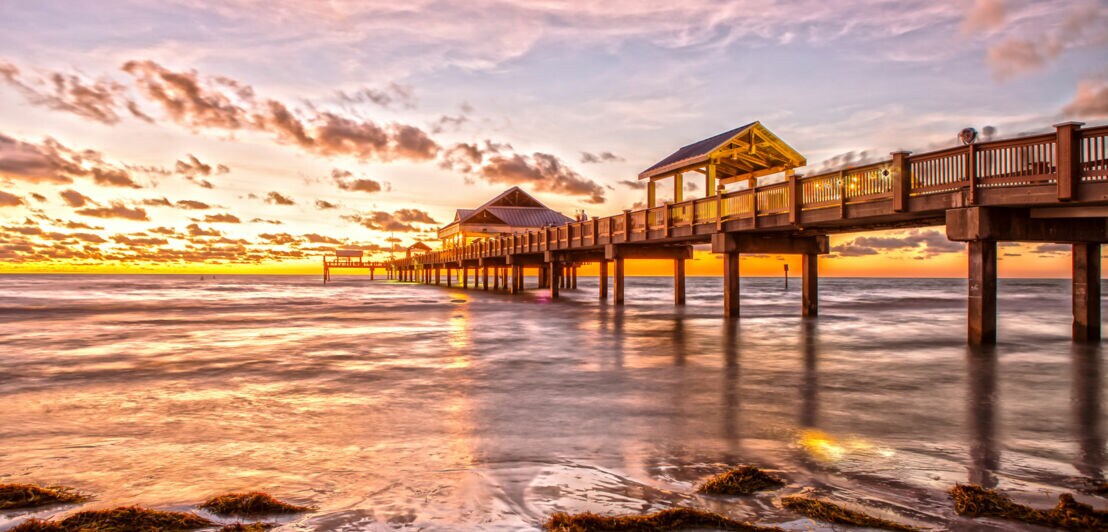 Der berühmte Pier 60 bei Sonnenuntergang mit goldgelbem Lichtspiel am Horizont.