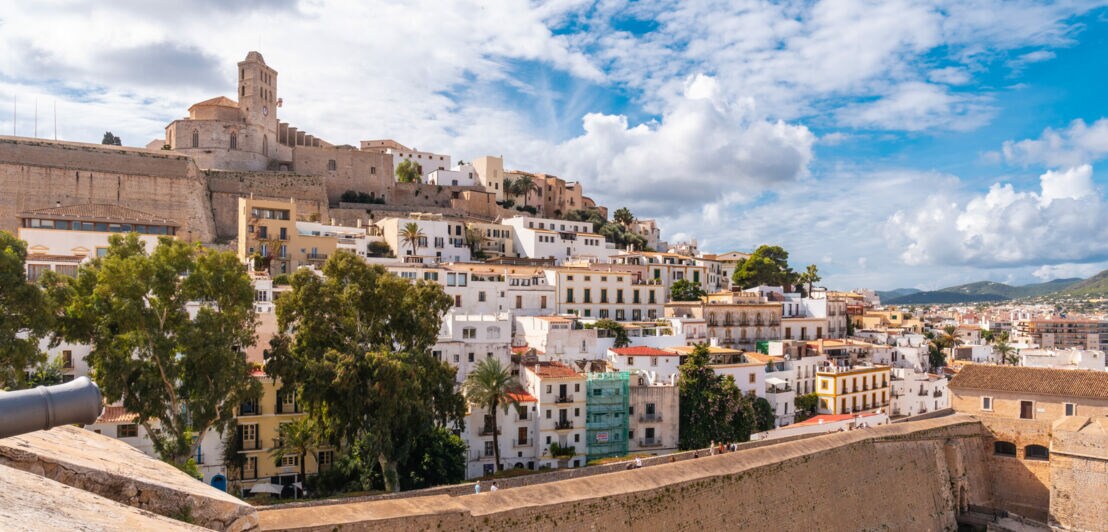 Blick auf die Altstadt von Ibiza mit weißen Häusern und der Kathedrale auf einem Hügel unter bewölktem Himmel