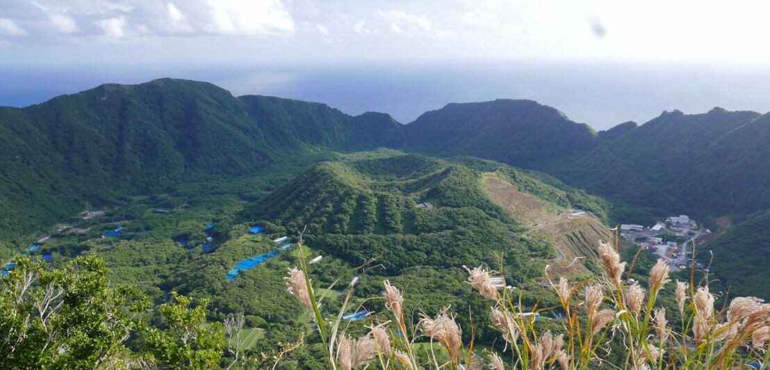 Blick von oben auf eine bewaldete Vulkaninsel.
