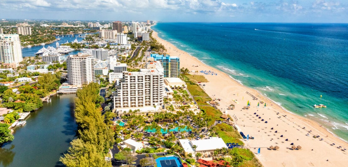 Luftaufnahme von Fort Lauderdale mit Hochhäusern und einem langen Strand am türkisblauen Meer.