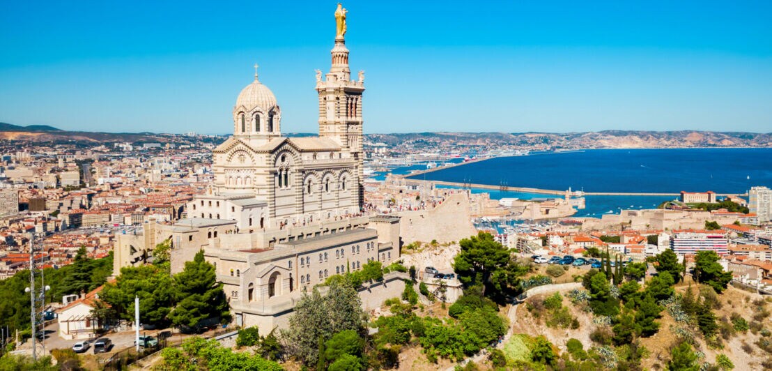 Basilika Notre-Dame de la Garde auf einem Hügel mit Blick auf Marseille und das Mittelmeer bei klarem Himmel