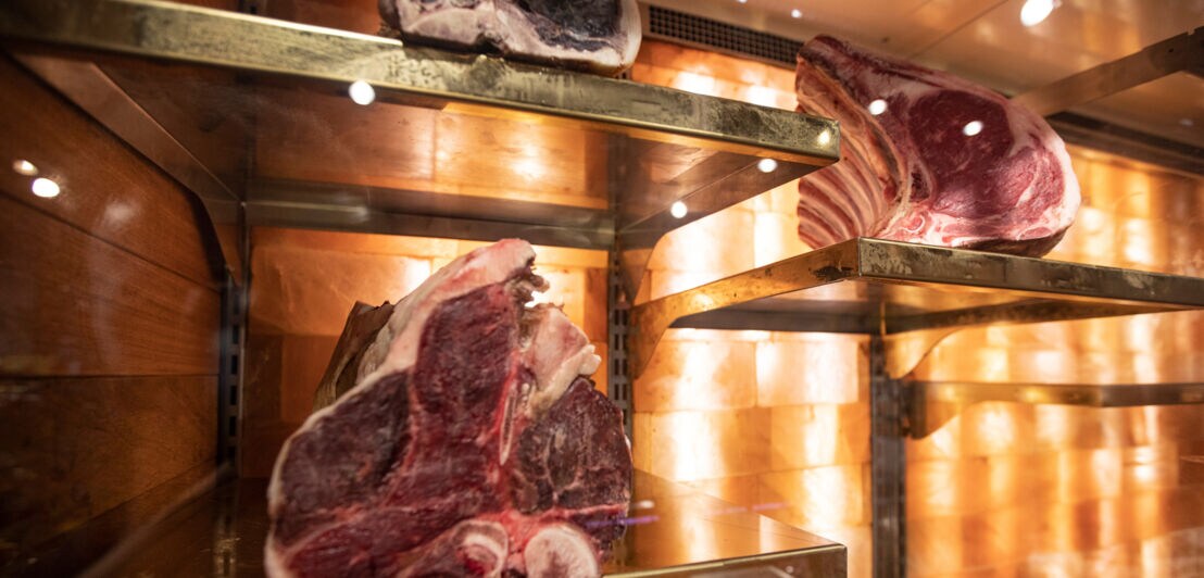 Dicke Fleischstücke mit Knochen lagern in einem klimatisierten Reifeschrank