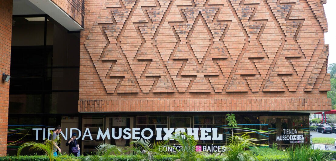 Fassade des Tienda Museo Ixchel mit Ziegelmuster in Form von Dreiecken und Pflanzen davor