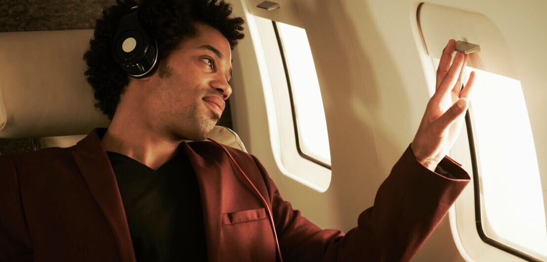 Ein Geschäftsmann sitzt in der Business Class und nutzt die Zeit zum Entspannen.