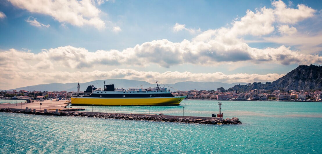 Fähre am Hafen mit Stadt und Bergen im Hintergrund unter bewölktem Himmel