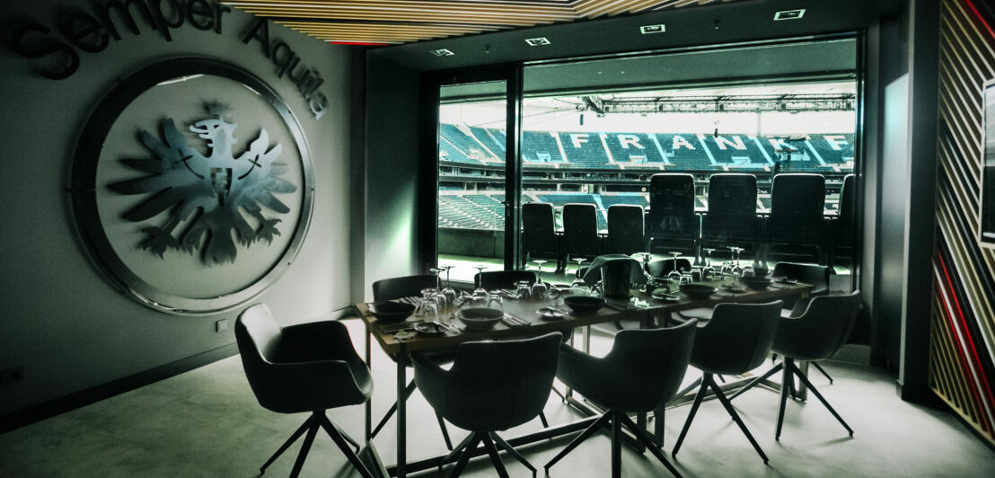 Eingedeckter Konferenztisch in einer Loge in einem Fußballstadion mit Frankfurter Adler-Wappen.