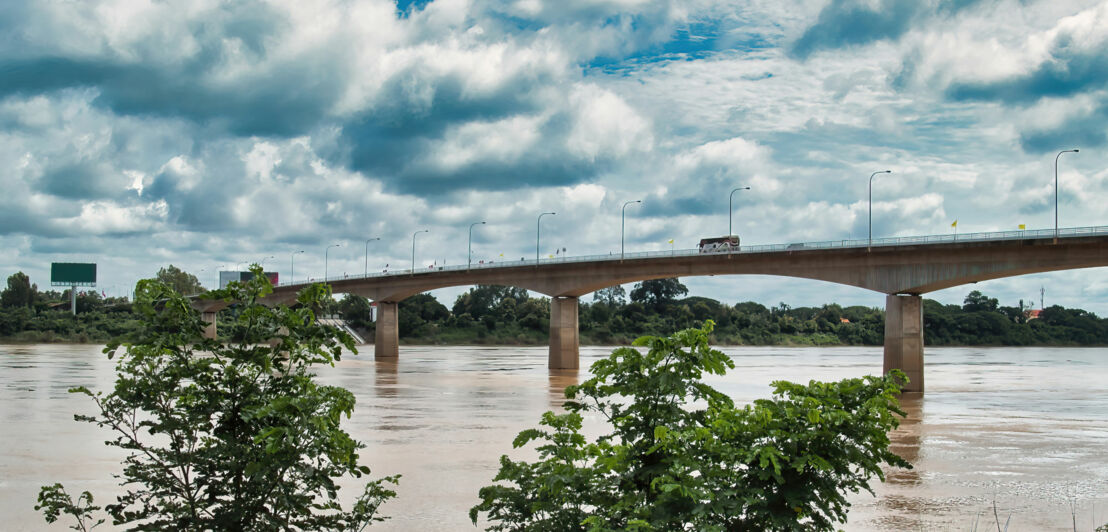 Die Thai-Lao Friendship Bridge, die Laos und Thailand verbindet. Sie ist eine große Betonbrücke mit mehreren Fahrspuren, die über einen breiten Fluss führt.