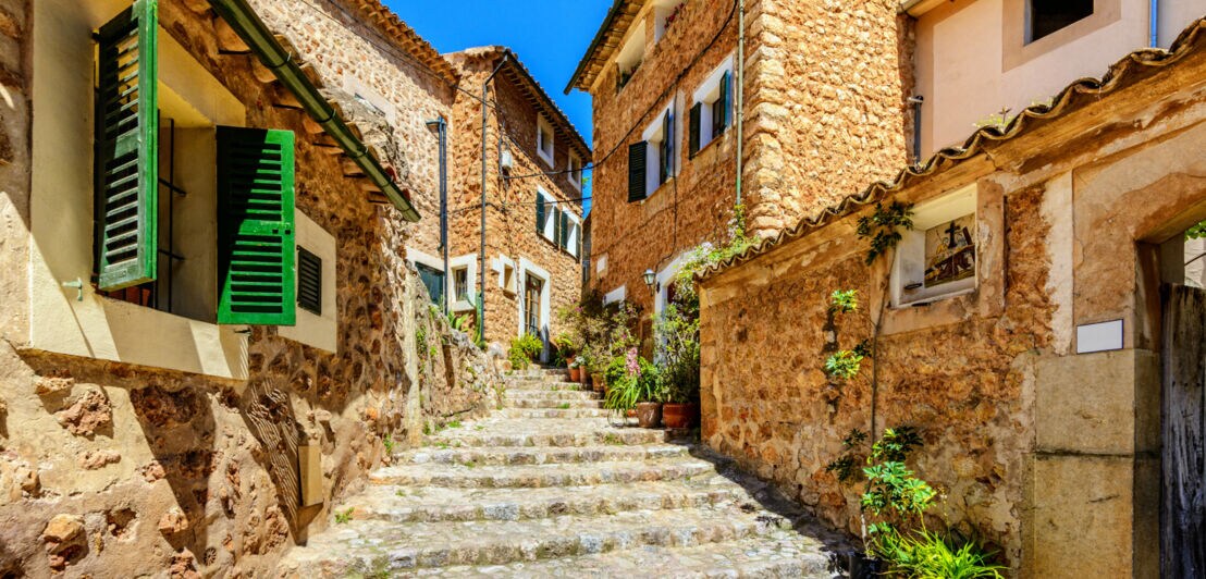 Steinweg mit Stufen zwischen traditionellen Häusern aus Naturstein mit grünen