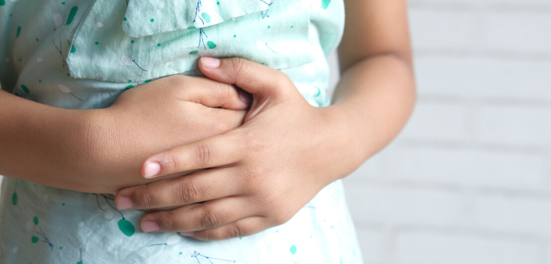 Ein Kind hält mit beiden Händen den Bauch.