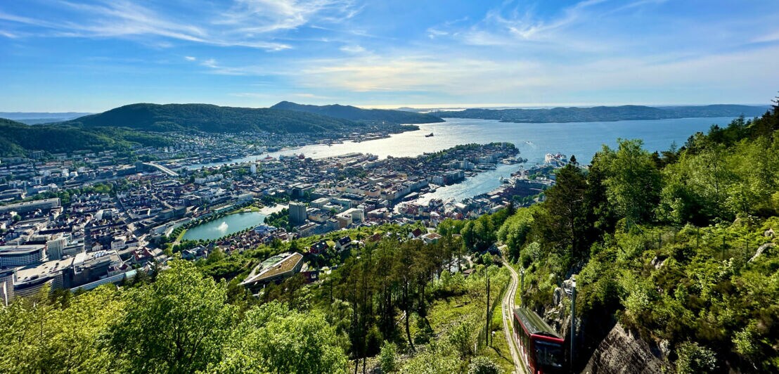 Luftaufnahme der Stadt Bergen in Norwegen mit Hafen, Stadt und Bergen unter blauem Himmel mit Sonne.
