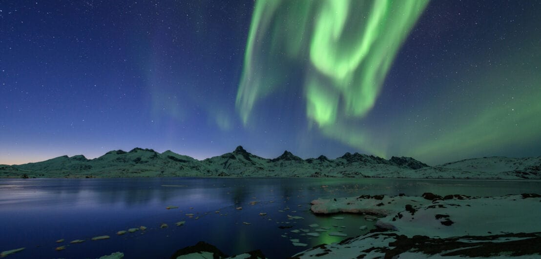 Grün leuchtende Aurora Borealis über dem Tasiilaq-Fjord in Ostgrönland.