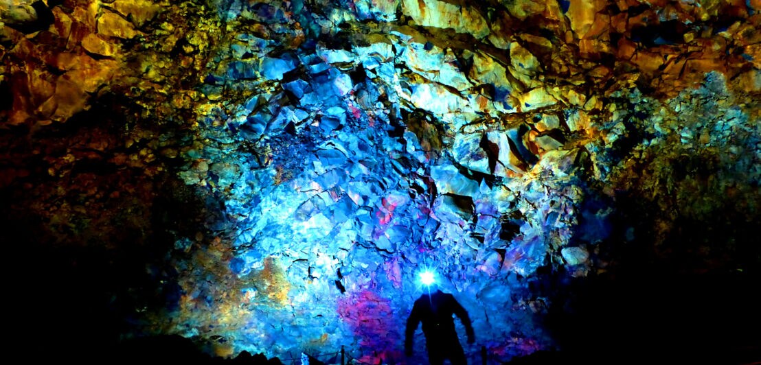 Höhle im Inneren des Vulkans Thrihnukagigur mit beleuchtetem bunt schimmernden Lavagestein.