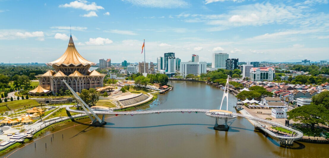 Panorama einer Stadt am Fluss mit Brücke und Palast mit goldenem Dach.