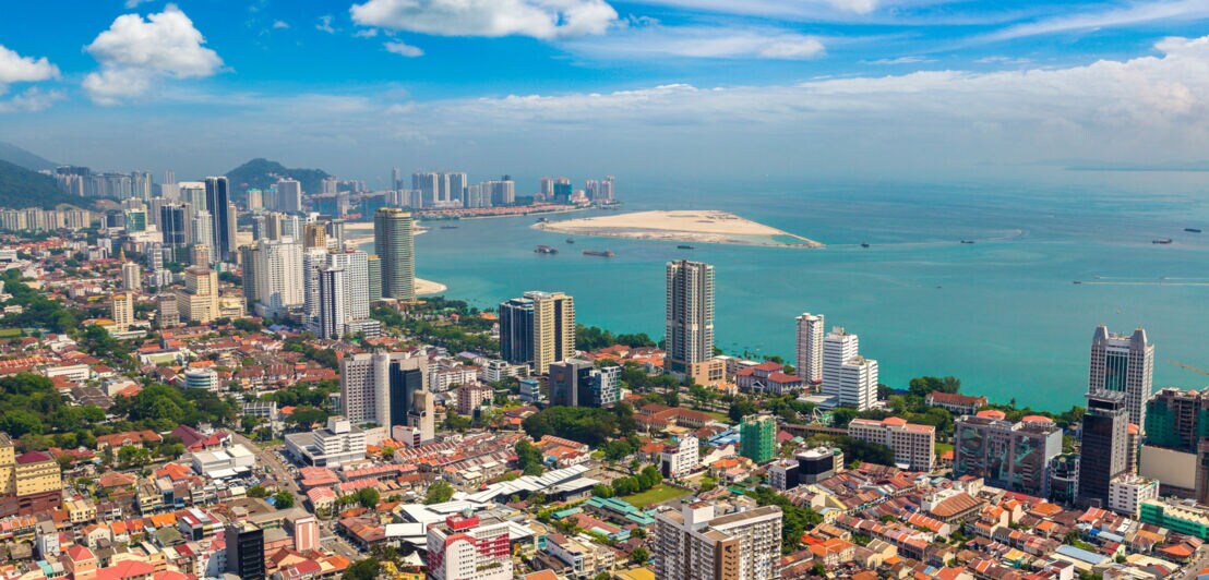 Luftaufnahme einer Großstadt am türkisfarbenen Meer.