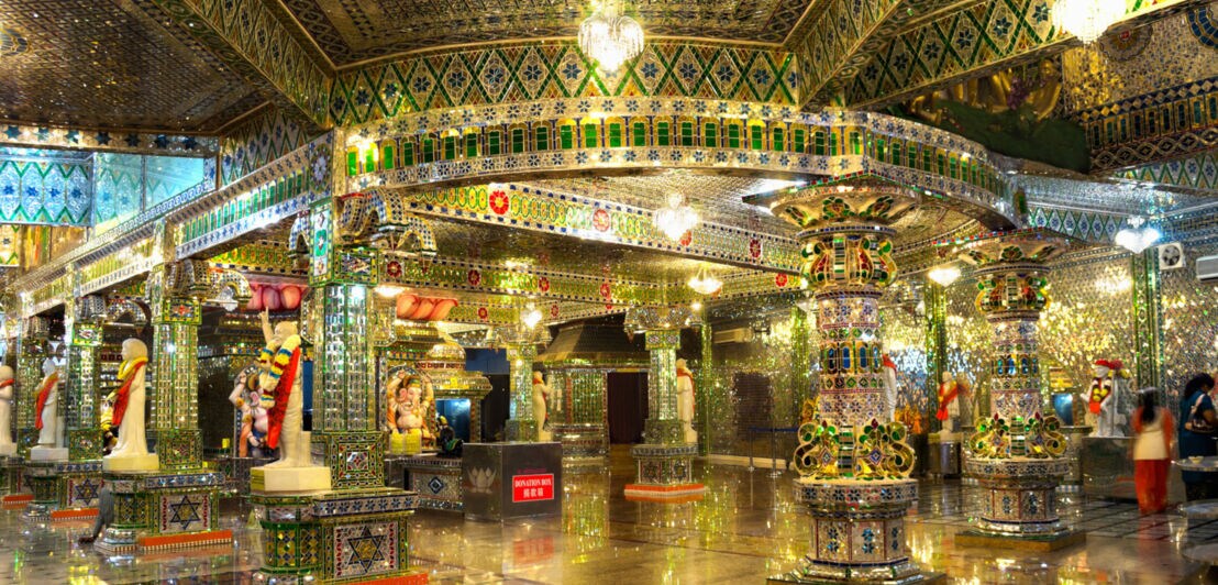 Prächtig verzierter Innenraum mit zahlreichen Säulen, Glasmosaiken und bunten Mustern an Decke und Boden.