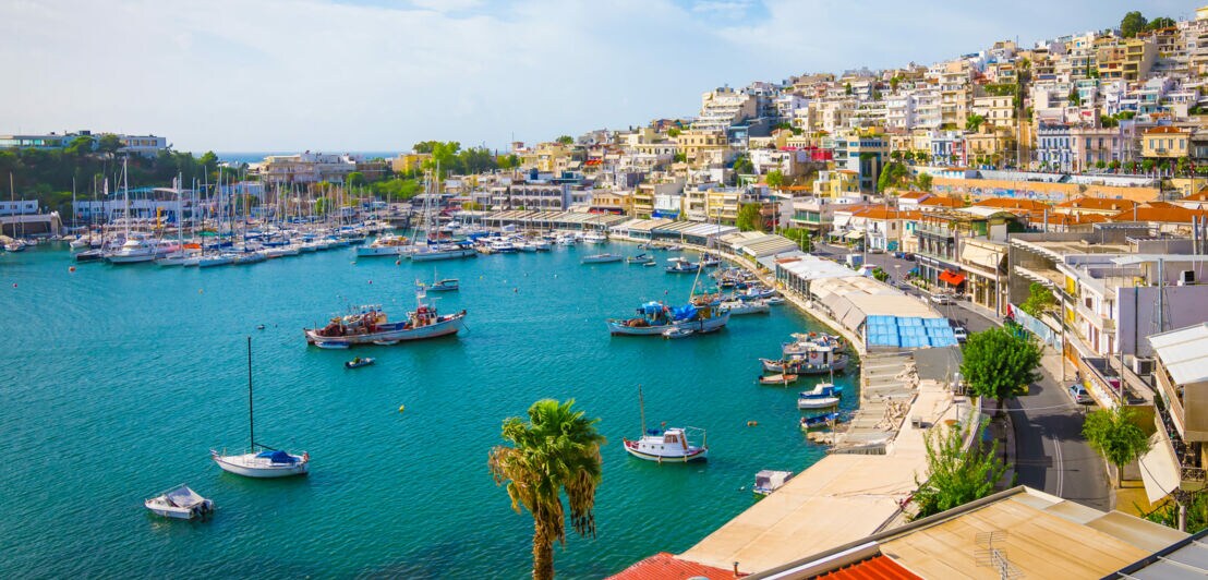 Vor einer kleinen Kirche mit rundem, roten Dach liegen kleine Boote im Hafen.