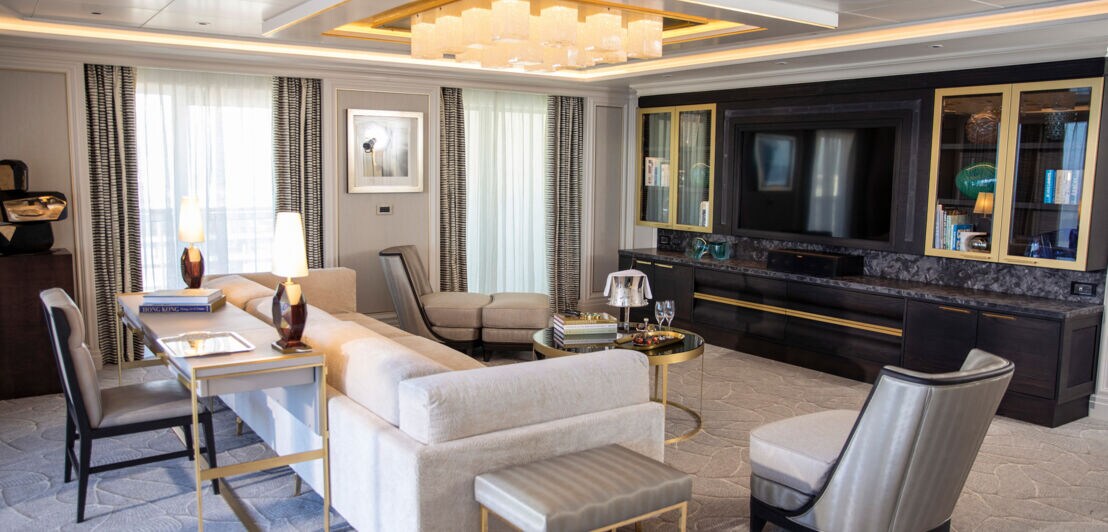 Luxuriöses Wohnzimmer mit hellgrauen Polstermöbeln und goldfarbenen Akzenten.