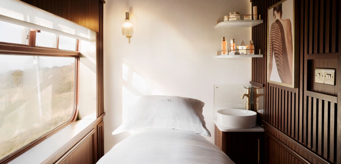 Eleganter Waggon mit Holzverkleidung, Behandlungsliege und Beauty-Artikeln.