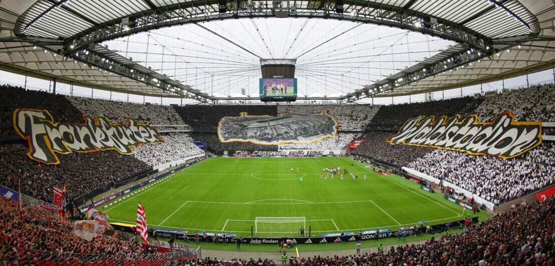 Fußballstadion mit gefüllten Zuschauerplätzen und großen Stoffbanner mit Aufdrucken