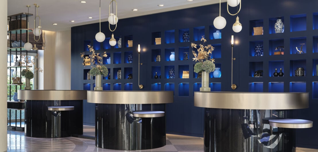 Moderne Hotellobby mit runden Empfangstresen und Designelementen vor blauer Wand.