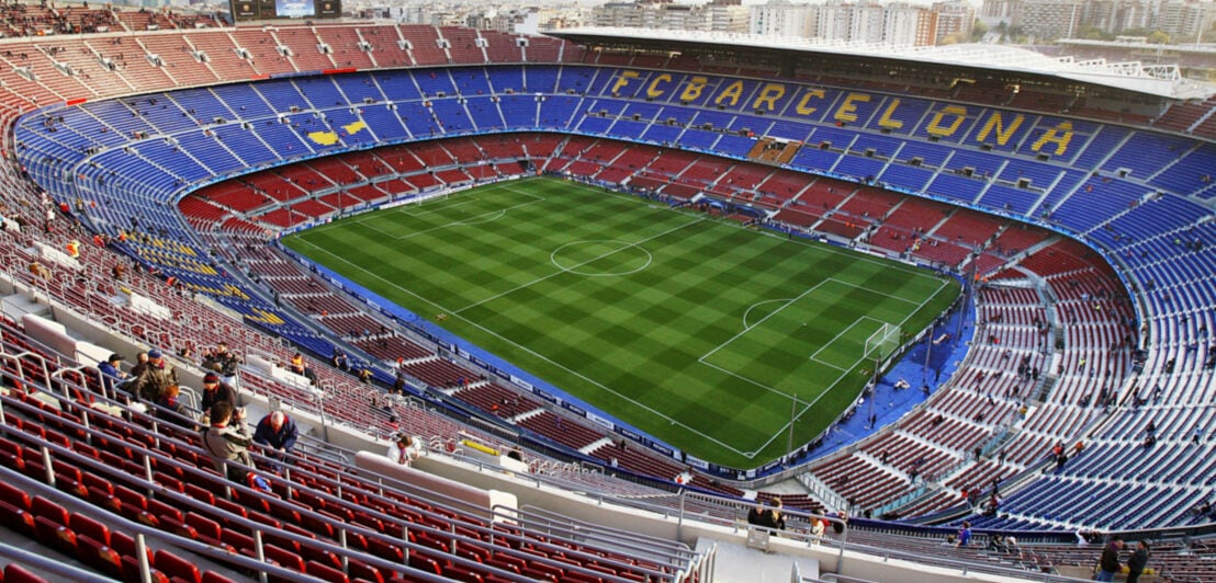 Vereinzelte Personen in einem Fußballstadion mit Aufschrift FC BARCELONA auf den Rängen.