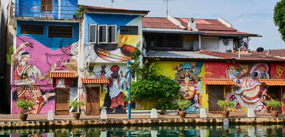 Häuserreihe mit bunter Street-Art auf der Fassade an einem Wasserkanal.