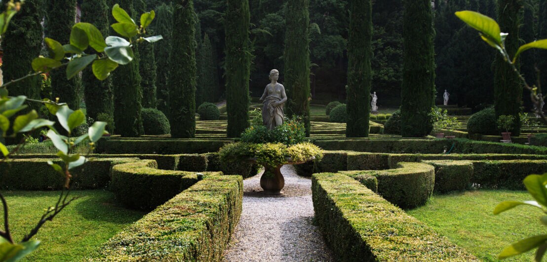 Renaissancegarten mit Zypressen und Steinstatuen in einem Heckenlabyrinth.