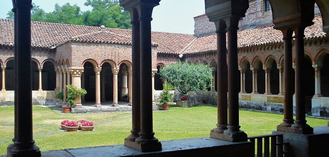 Kreuzgang in einem Kloster mit Innenhof mit Rasenfläche.