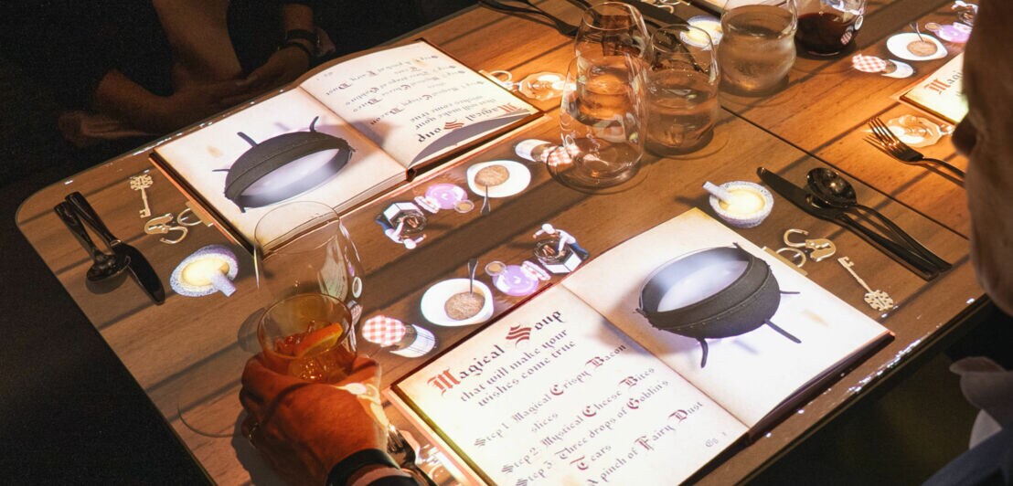 Lichtprojektionen auf einem eingedeckten Esstisch.