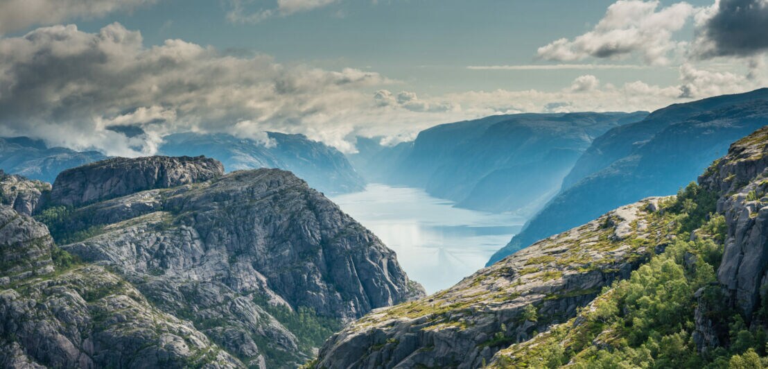 Blick auf begrünte Felsen, die einen Fjord umgeben.
