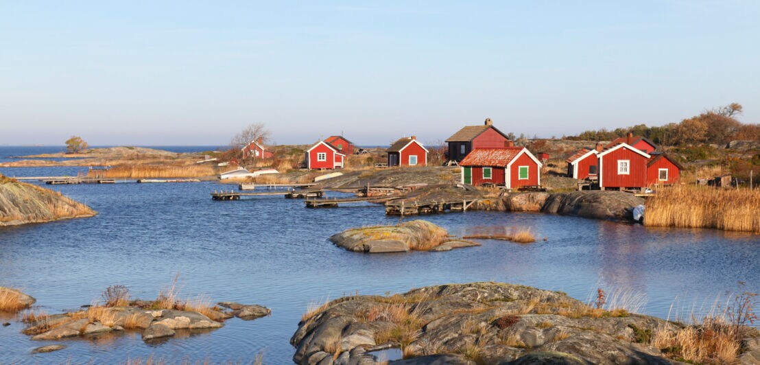 Blick auf rote Holzhäuser auf einer Insel.