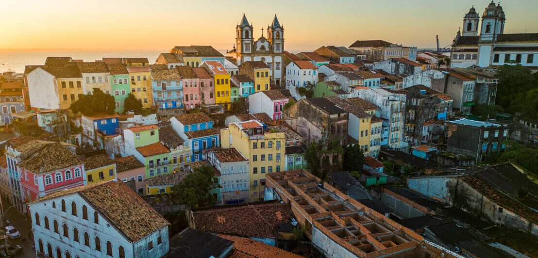 Auf einem Hügel liegt eine Stadt mit kleinen bunten Häusern.