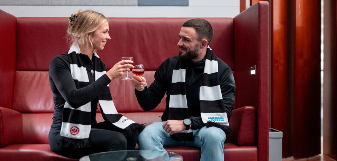 Ein Paar mit Weingläsern in der Hand prostet sich zu.