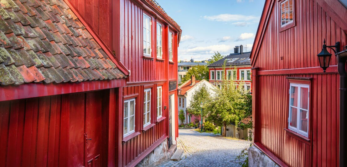 In einer kleinen Straße stehen rote Holzhäuser.