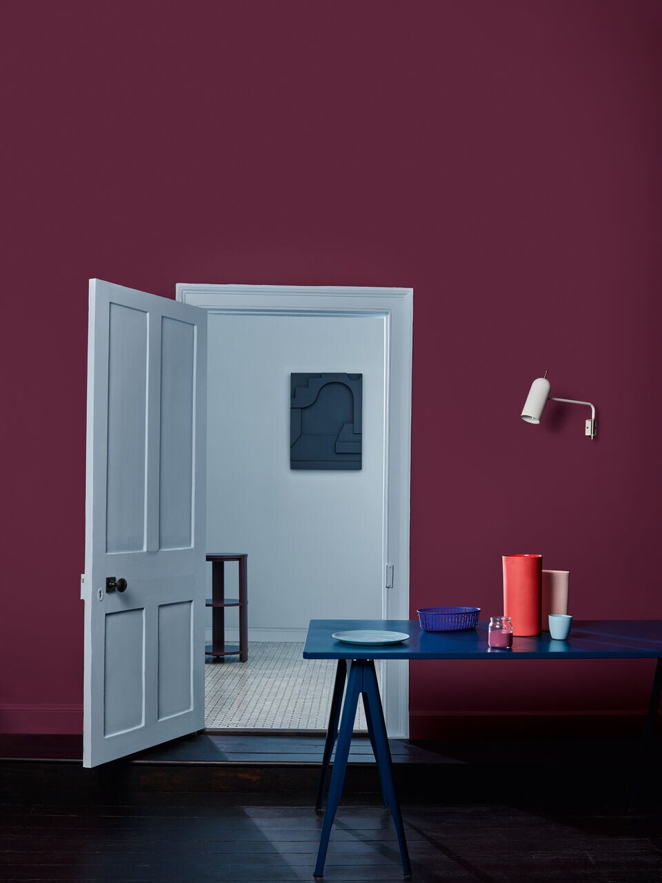 Ein schlicht eingerichteter Raum mit einem blauen Tisch, einer weißen Wand und satt-pinken Wänden