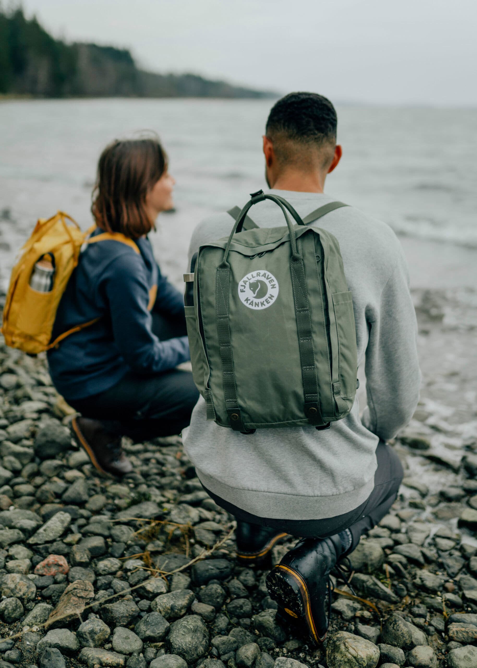 Rückansicht von Frau und Mann mit Rucksäcken am Meer