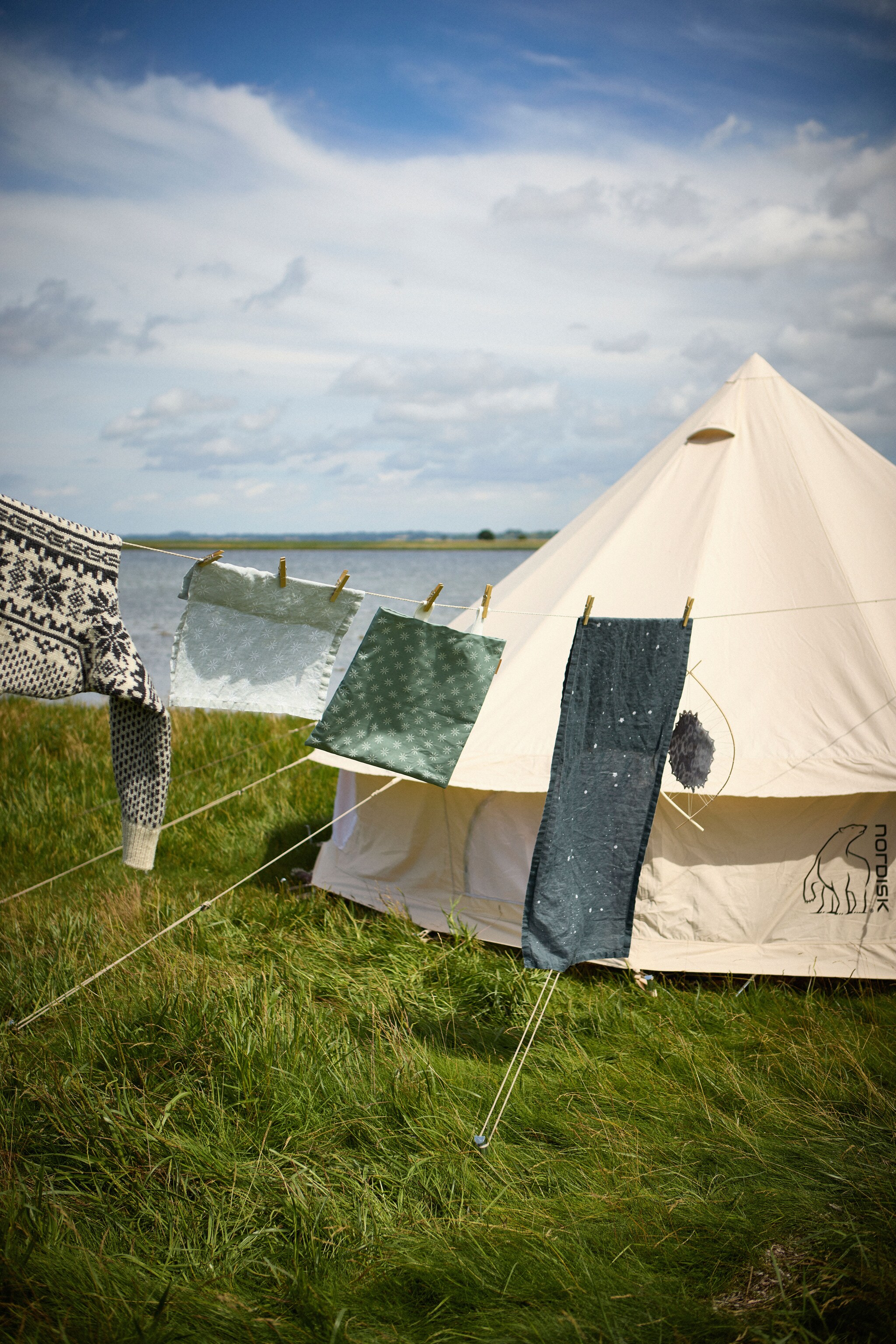Wäscheleine mit Textilien vor einem Zelt in der Natur